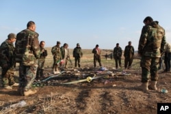 FILE - Kurdish Peshmerga forces inspect a site in Hardan village in northern Iraq, Dec. 22, 2014, where Islamic State group fighters allegedly executed people from the Yazidi sect captured when they swept through the area in August.
