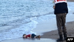 FILE - A Turkish police officer observes the body of migrant child Aylan Shenu on the beach at Bodrum, southern Turkey. Syrians Muwafaka Alabash and Asem Alfrhad were convicted of human trafficking in the deaths of the child and his parents.