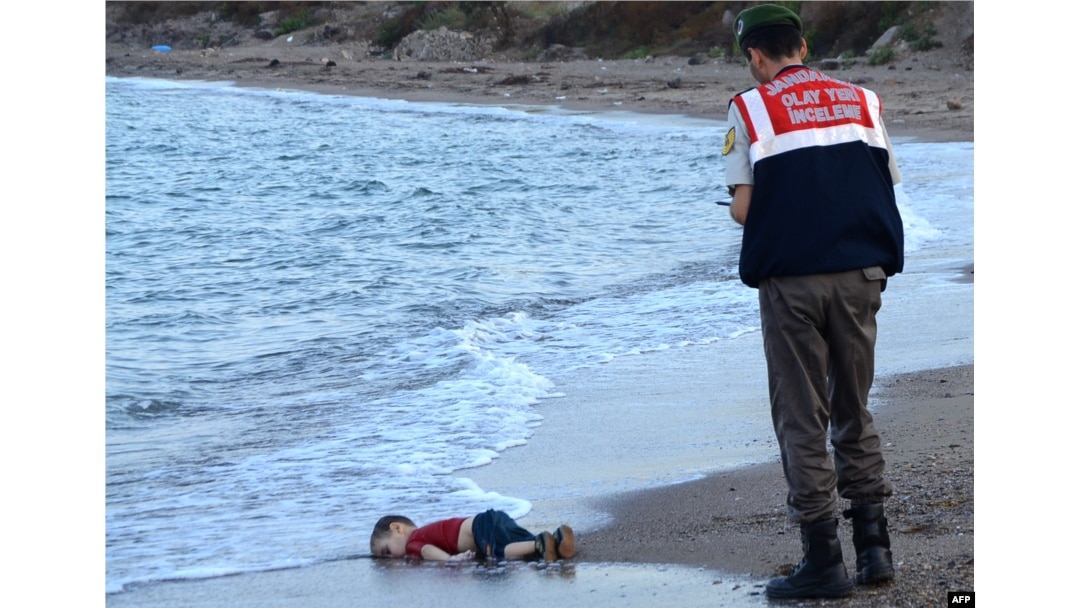 A police officer stands next to a migrant child's body in Bodrum, southern Turkey, on Sept. 2, 2015, after a boat carrying refugees sank while reaching the Greek island of Kos.