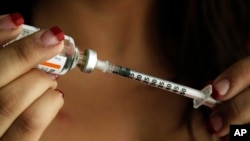 FILE - A woman holds a syringe with insulin.