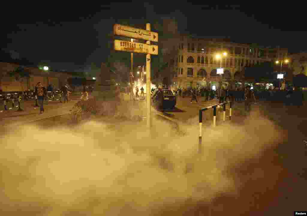 Anti-Morsi protesters run from smoke from a tear gas canister thrown by riot police, during clashes in front of the presidential palace in Cairo, Egypt, December 4, 2012. 