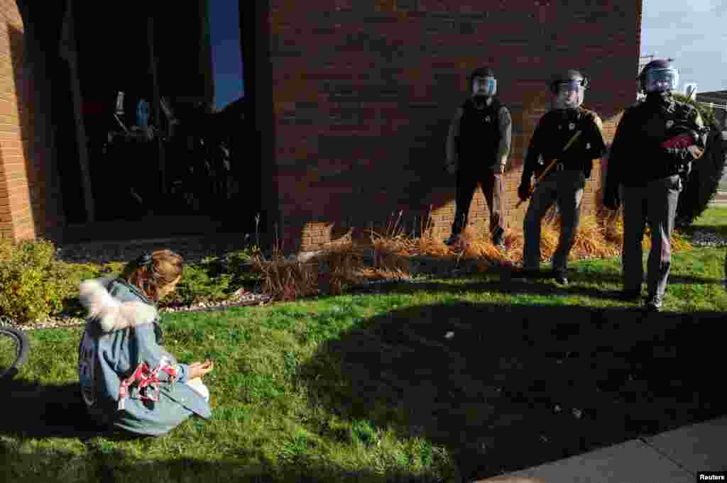 A woman kneels in front of police during a protest in Bismarck against plans to pass the Dakota Access pipeline under Lake Oahe and near the Standing Rock Indian Reservation, North Dakota, Nov. 14, 2016.