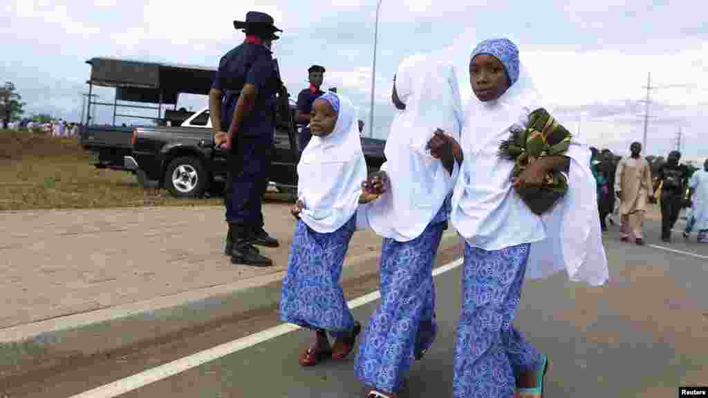 Muslim girls walk pass security officers on their way to prayers during Sallah festival in Abuja.