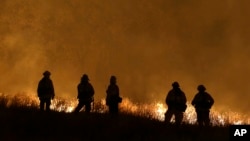 Firefighters stand guard as flames from the Butte Fire approach a containment line in San Andreas, California, Sept. 12, 2015.