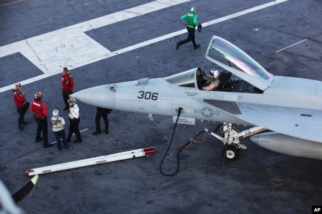 Flight crew members of the USS John C. Stennis aircraft carrier congregate by an F/A-18 fighter jet, Dec. 21, 2018.