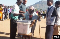 Polling monitors offer assistance as an elderly woman casts her vote in Tuesday's election in Malawi. (L Masina/VOA)