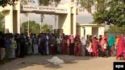 People look on as the body of Hindu monestary worker Nityaranjan Pandey, 60, is covered in a cloth in the street after he was hacked to death at Hemayatpur Upazilla in Pabna, Bangladesh, June 10, 2016. 