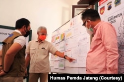 Gubernur Jawa Tengah Ganjar Pranowo (tengah) mengamati grafik kasus COVID-19 dalam kunjungan ke Kudus, Minggu 13 Juni 2021. (Foto: Courtesy/Humas Pemda Jateng)
