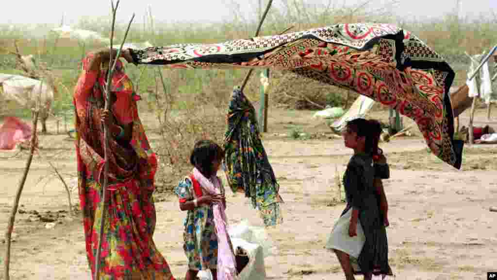 Seorang ibu di distrik Kutch, Gujarat di India, memakai sarinya untuk melindungi anaknya dari panas yang mencapai 50 derajat Celsius pada 2001. Pada 1998, sekitar 2.541 kematian terjadi di India akibat gelombang panas.