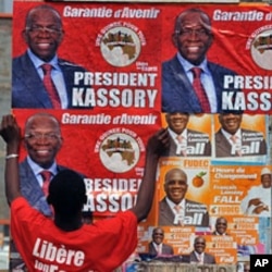 A man puts up electoral posters on a wall in a street of Conakry ahead of Guinea's first free election since independence in 1958., 24 Jun 2010