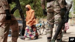 A woman passes Nigerian soldiers at a checkpoint in Gwoza, Nigeria, a town newly liberated from Boko Haram, in this photo dated April 8, 2015. Each month brings new reports of atrocities committed by the militants.