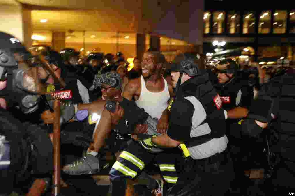 지난 21일(현지시간) 미국 노스캐롤라이나주 샬럿의 아파트 주차장에서 흑인 남성인 키스 라몬트 스콧이 경찰 총격으로 사망한 이후 항의시위가 격화되고 있는 가운데, 경찰과 시위대가 시위 도중 발생한 부상자를 안전한 장소로 옮기고 있다.