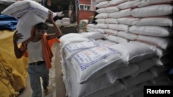 A laborer unloads sacks filled with rice at a wholesale grain market in the northern Indian city of Chandigarh, July 29, 2014.