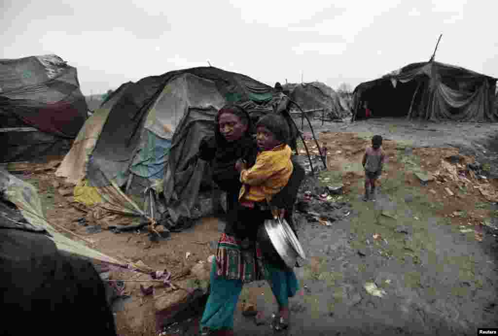 A woman carries her daughter on her way to fetch water from a nearby tap in a slum on the outskirts of Islamabad, Pakistan. 