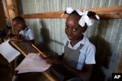 Schoolgirls work on an assignment at the Bethesda Evangelical School in Canaan, June 24, 2015. Much of Haiti's school system is privatized, and settlers in Canaan wasted no time in setting up their own schools, many run by churches.