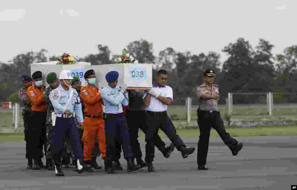 Members of the National Search and Rescue Agency carry coffins containing bodies of the victims of the AirAsia Flight 8501, at the airport in Pangkalan Bun, Indonesia, Jan. 7, 2015.