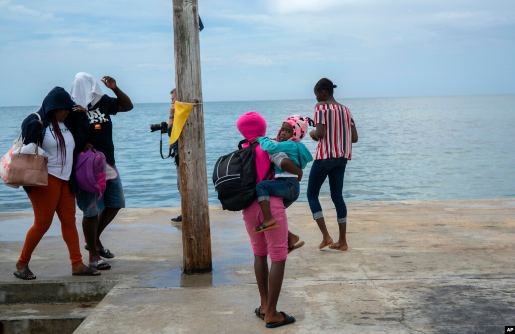 Una mujer lleva una niña en brazos tras ser evacuada del Cayo Sweeting&#39;s en Las Bahamas, el sábado, antes del paso del huracán Dorian. Gran Bahama, agosto 31 de 2019.&nbsp; AP/Ramón Espinosa.