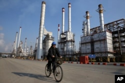 FILE - Iranian oil worker rides his bicycle at Tehran's oil refinery south of the capital Tehran, Iran.