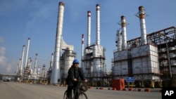 FILE - Iranian oil worker rides his bicycle at the Tehran's oil refinery south of the capital Tehran, Iran. Energy-poor Turkey relies on Iran's oil and is the largest importer of Iranian natural gas. 