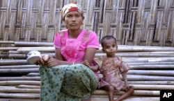 FILE - In this March 17, 2017, image made from video, Rosmaida Bibi, right, who suffers from severe malnutrition, sits with her 20-year old mother Hamida Begum outside their makeshift shelter at the Dar Paing camp, north of Sittwe, Rakhine State, Myanmar.