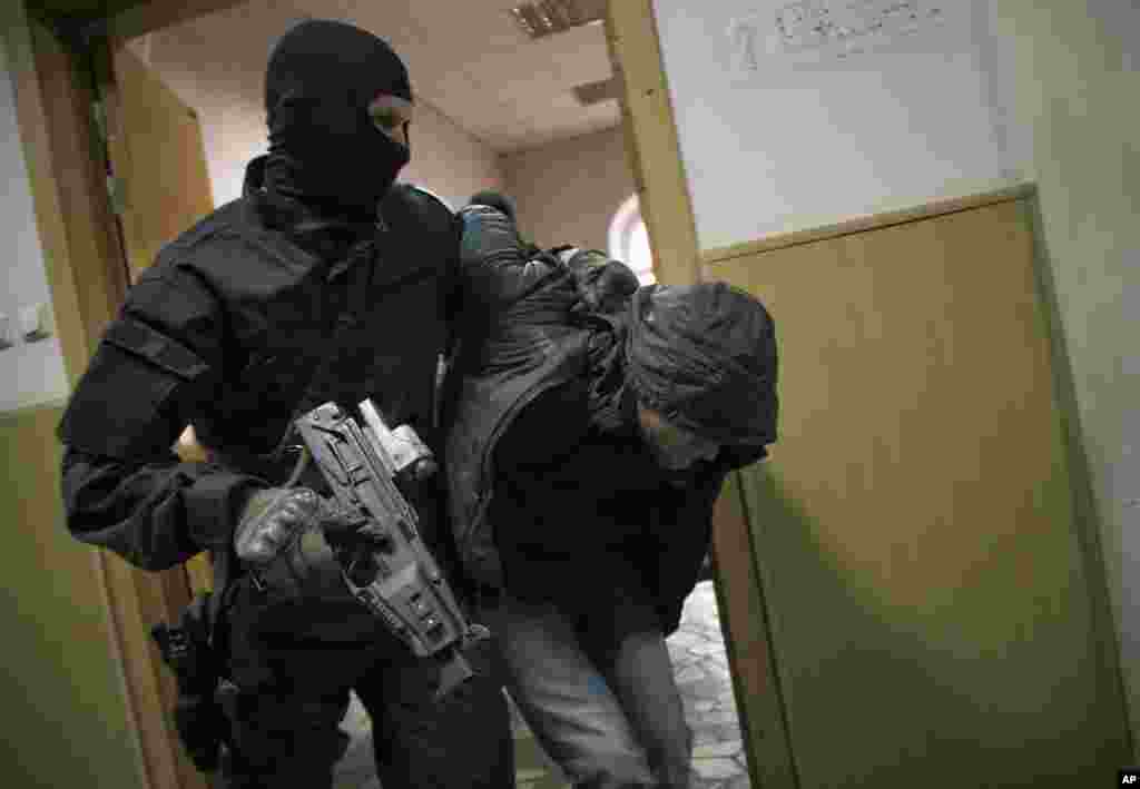 Police escort a man believed to be one of five suspects in the killing of prominent Russian opposition figure Boris Nemtsov in a court room in Moscow, Russia.