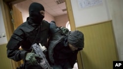 Police escort a man believed to be one of five suspects in the killing of Boris Nemtsov in a court room in Moscow, Russia, Sunday, March 8, 2015. Five suspects in the killing of prominent Russian opposition figure Boris Nemtsov have been delivered to the 