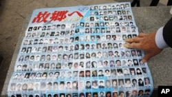 A family member of a South Korean who, he said, was abducted by North Korea, looks at pictures of Japanese people who were believed to be abducted by the North, during a campaign demanding for a legislation of North Korean human rights laws and repatriati
