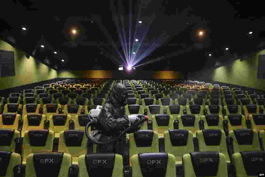 A staff member sprays disinfectant inside a cinema ahead of reopening to the public after closing due to the Covid-19 coronavirus, in Kathmandu, Nepal.