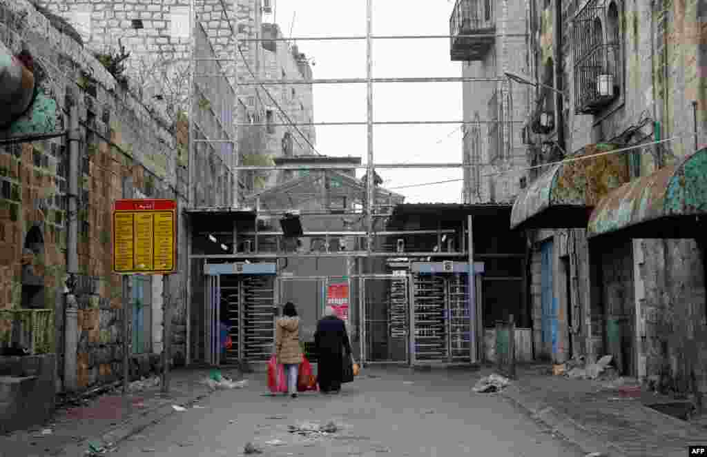 Two Palestinian women approach a checkpoint to cross into the Israeli-controlled Shuhada Street in the divided town of Hebron, in the Israeli occupied West Bank.