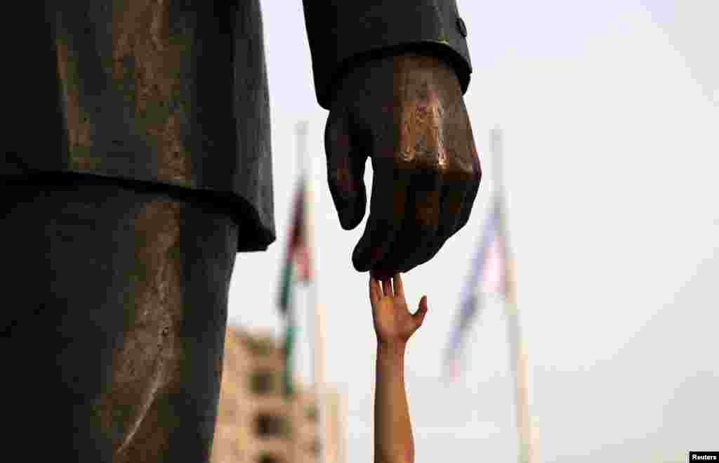 A Palestinian man touches the Mandela statue during the inauguration of Nelson Mandela Square in the West Bank city of Ramallah, April 26, 2016.