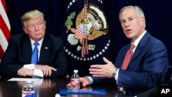 FILE - President Donald Trump listens as Texas Gov. Greg Abbott speaks during a briefing on hurricane recovery efforts, Oct. 25, 2017, in Dallas. 