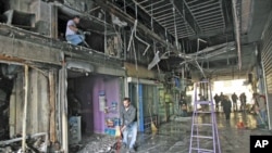 Workers start clean-up operations in a burned out shopping arcade after a night of violence that followed the Greek parliament approval of a deeply unpopular austerity bill in Athens, Greece, February 13, 2012.