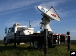 A NOAA mobile storm-chasing radar vehicles is deployed outside a bat cave at dusk.