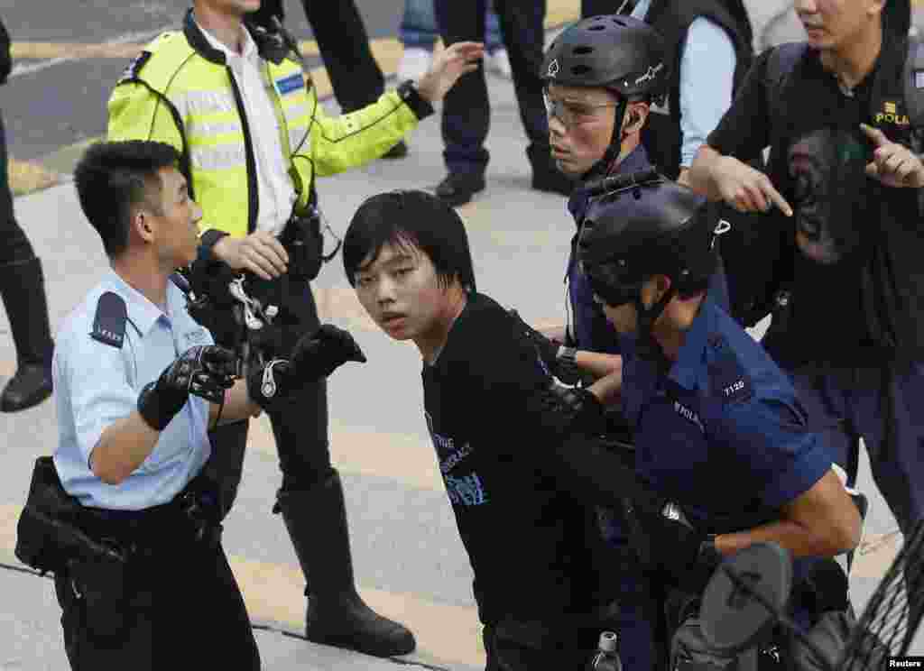 Polisi menahan seorang mahasiswa yang menolak meninggalkan jalan utama distrik Mong Kok di Hong Kong (25/11).