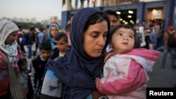 Syrian refugees disembark from a Greek ferry after arriving in the port of Piraeus near Athens, June 14, 2015.