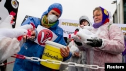 FILE - A demonstrator feeds mock antibiotics to chicken puppets during a protest denouncing industrial livestock farming and current agricultural policies in Berlin. 