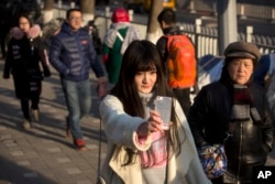 Online web performer Wang Weiying, 18, broadcasts a live stream from her smartphone as she walks down a street in Beijing, Feb. 28, 2016.