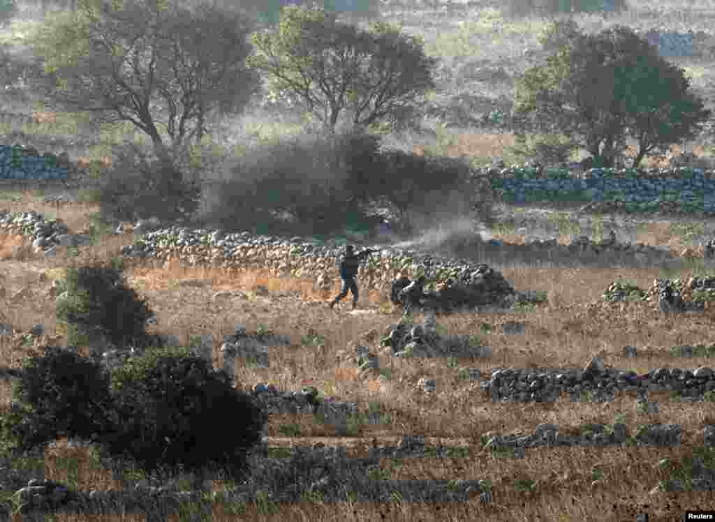 Syrian army soldiers fire during a battle with rebels near the border fence with the Golan Heights, Sept. 1, 2014.