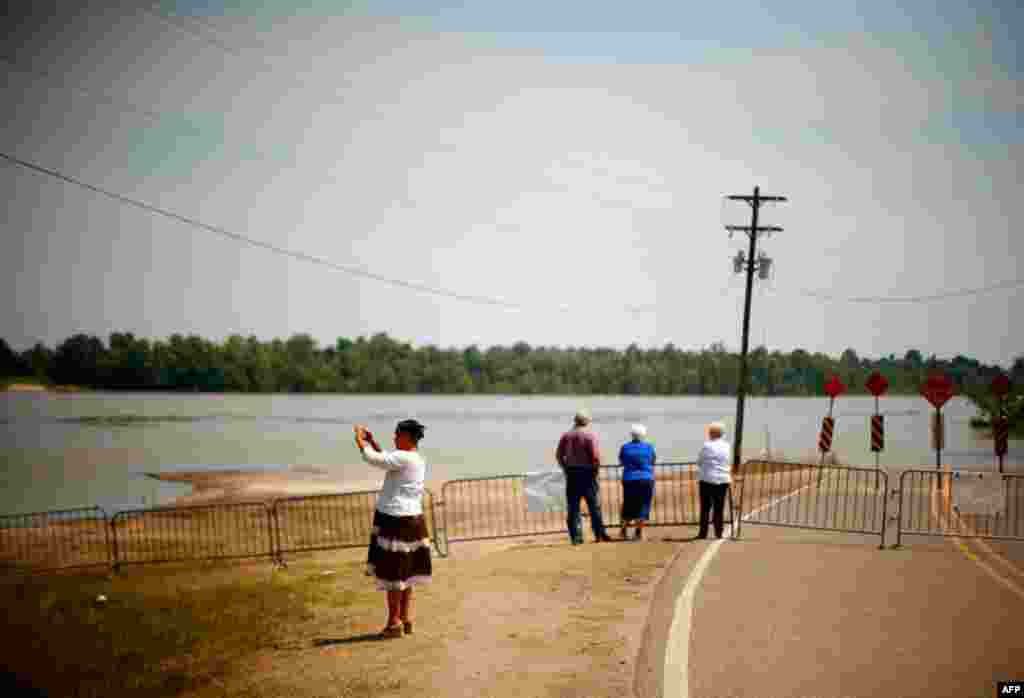 Residents look out at the Atchafalaya River as floodwaters approach Melville, Louisiana May 15. Army engineers on Saturday opened a key spillway to allow the Mississippi River to flood thousands of homes and crops, but spare New Orleans and Baton Rouge. (