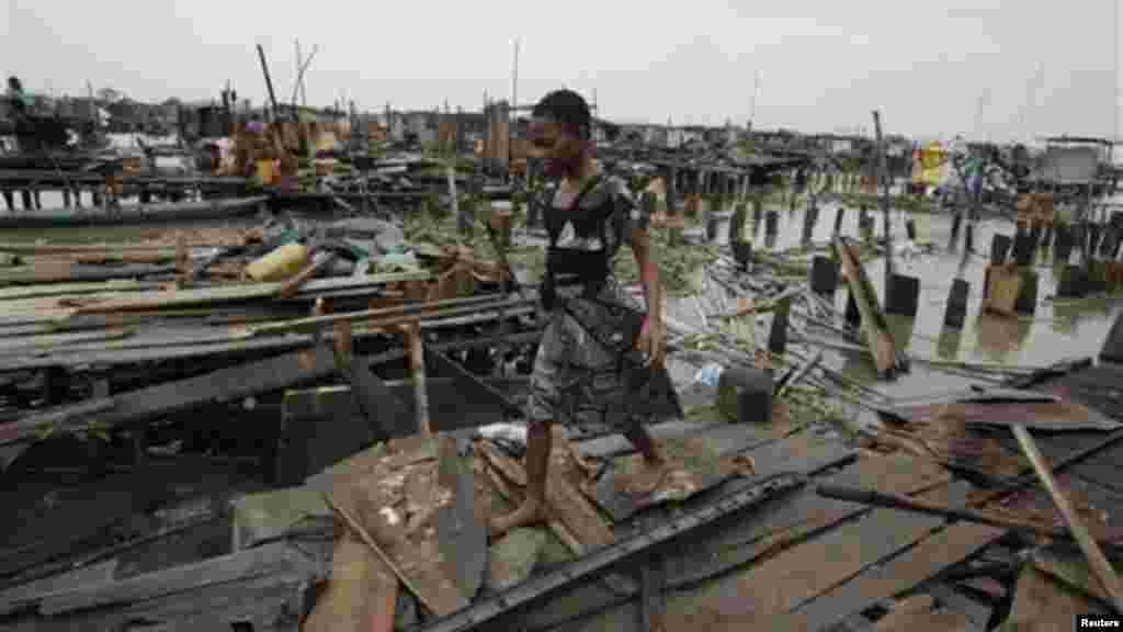A woman walks on ruins of her demolished illegal stilt house in Legas.