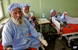 Afghan men, among nearly a dozen people who had their fingers cut off by Taliban fighters as a punishment for voting in this weekend's presidential runoff, rest in a hospital in Herat, Afghanistan, June 15, 2014.