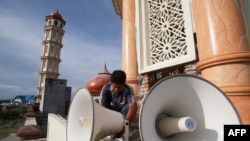 FILE – A worker inspects a loudspeaker at a mosque in Aceh province, Indonesia, June 28, 2014.