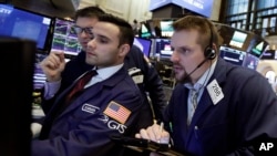 Trader Michael Milano, right, works with specialists Karan Virdi, center, and David Haubner, background, on the floor of the New York Stock Exchange, Jan. 9, 2018.