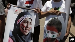 Two protesters carry posters with pictures of unidentified relatives in Syria, with the Syrian flag colors painted on their faces during an anti-Syrian regime rally near the Syrian embassy in Cairo, Egypt, July 5, 2011