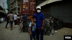 Em Savin stands outside his shipping container as his team wraps up loading and repairing bikes.(Kiana Duncan/VOA Khmer)