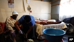 AIDS patient Anna Bosigo (L) has her leg massaged by volunteer worker Lydia Mbhalo, of the Sakhi-Sizwe AIDS care initiative, in the Orange Farm township, south of Johannesburg, August 23, 2011.