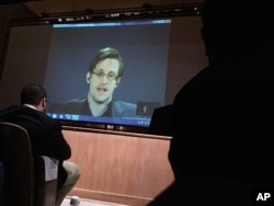 FILE - Former National Security Agency contractor Edward Snowden, center, speaks via video conference to people in the Johns Hopkins University auditorium in Baltimore, Feb. 17, 2016.