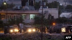 Israeli soldiers stand next to their vehicles in the village of Halhul, near the West Bank town of Hebron, where the bodies of the three missing Israeli teenagers were found, June 30, 2014. 