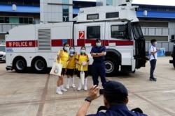 在“全民国家安全教育日“展览当中，小学生在警察水炮车旁边拍照