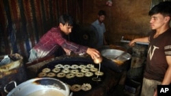 Para pedagang di sebuah toko kue tradisional menyiapkan camilan untuk Hari Raya Idul Fitri, di Kabul, Afghanistan, 22 Mei 2020. (Foto: AP)